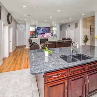 Modern open floor plan kitchen and living area with granite countertops and wood flooring.