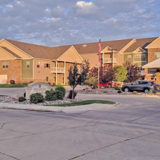 A view of a residential apartment complex with landscaped surroundings and a flag in the foreground.