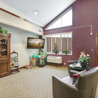 A cozy living room with a television, plants, and comfortable seating.