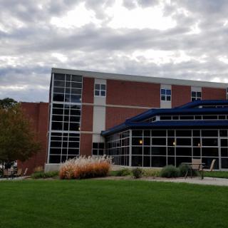 A modern architectural building surrounded by landscaped grass and under a cloudy sky.