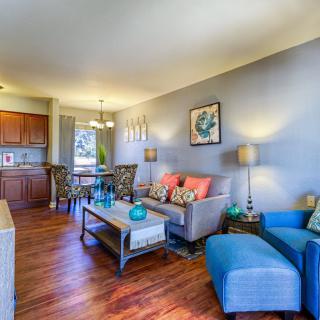 A modern and cozy living room with hardwood floors, featuring a sofa, armchair, coffee table, and stylish decor.