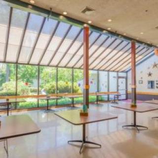 A spacious, well-lit cafeteria with large windows and modern furnishings.
