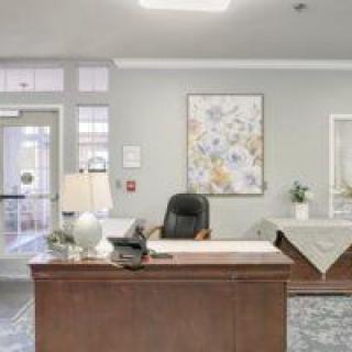 A reception area featuring a desk with a chair, lamp, and decorative artwork on the wall.
