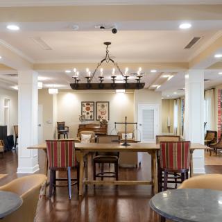 A spacious and elegantly designed living room with a dining area, featuring a chandelier and wooden flooring.