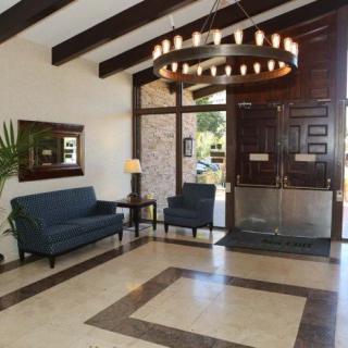 A spacious lobby area with blue sofas and a chandelier, featuring wooden ceiling beams and a large entrance.