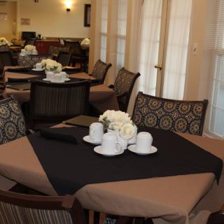 A cozy restaurant dining area with neatly set tables, featuring white flowers and cups.