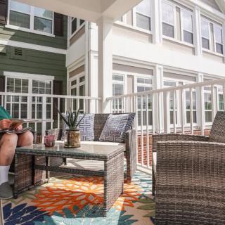 A cozy patio seating area with wicker furniture and a colorful rug.