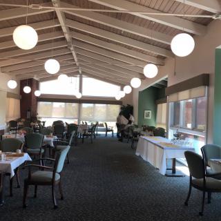 A modern dining area with tables and chairs, featuring large windows and spherical lighting fixtures.