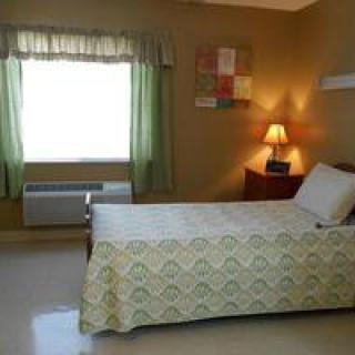 A simple bedroom with a single bed and soft lighting.