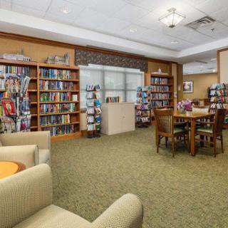 A cozy library space featuring bookshelves filled with books, comfortable seating, and tables for reading or studying.