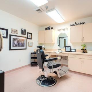 A cozy barber shop interior featuring a styling chair, wooden cabinets, and decor on the walls.