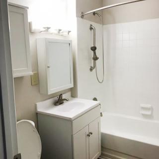 A small bathroom with white fixtures including a sink, toilet, and bathtub.