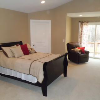 A cozy bedroom with a large bed, armchair, and natural light from the window.