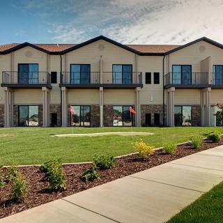 A modern building with large windows and a well-maintained lawn.