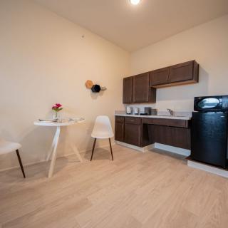 A compact kitchen and dining area with modern minimalist design, featuring wooden cabinets, a small dining set, and essential appliances.