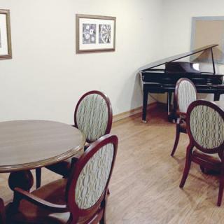 A cozy room featuring a grand piano, round tables, and elegant chairs.