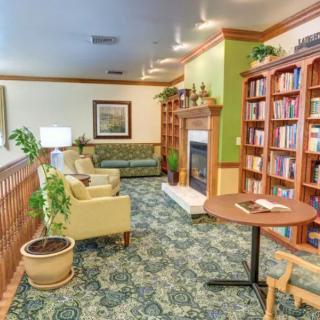A cozy library space with bookshelves, armchairs, and a fireplace.