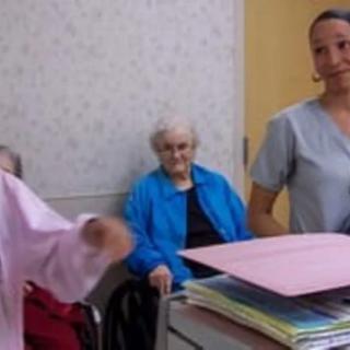 A caregiver assisting an elderly person in a nursing home setting.