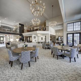 A spacious and elegantly designed dining area featuring modern furnishings and grand chandeliers.