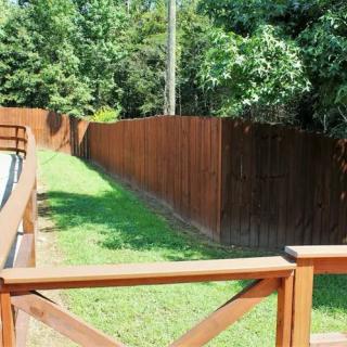 A backyard view featuring a wooden fence surrounded by grass and trees.
