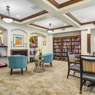 A cozy library lounge area with bookshelves, comfortable seating, and elegant interior design.