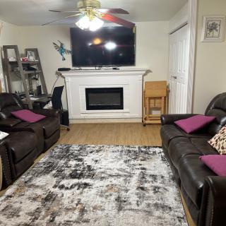 A cozy living room with two leather sofas, a fireplace, and a large TV mounted above it.