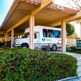 A white transportation van parked under an awning at the entrance of a building.