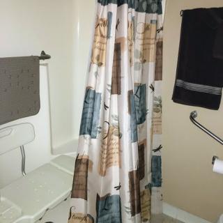 A bathroom featuring a patterned shower curtain and towels hanging on the wall.
