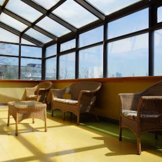 A sunny sunroom featuring wicker furniture and a glass ceiling, perfect for relaxation.