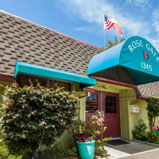 The entrance of a cozy inn with an American flag and vibrant signage on a clear day.