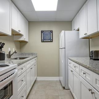 A modern kitchen with white cabinets and appliances.
