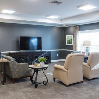 A cozy living room with modern decor, featuring comfortable armchairs and a large television.