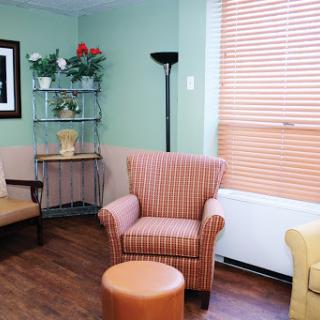 A cozy waiting room featuring comfortable seating, a small table, and decorative plants.