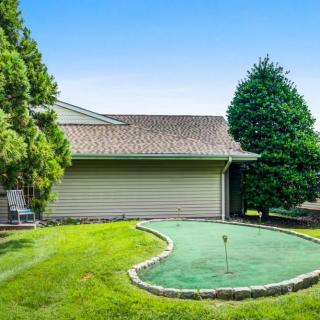 A cozy backyard featuring a putting green surrounded by lush grass and trees.