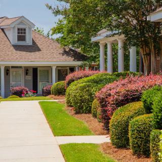 A well-maintained house with a beautifully landscaped garden, featuring manicured bushes and a clear pathway, on a sunny day.