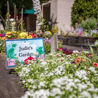 A vibrant garden labeled with a sign reading 'Julies Garden,' showcasing a variety of colorful flowers.