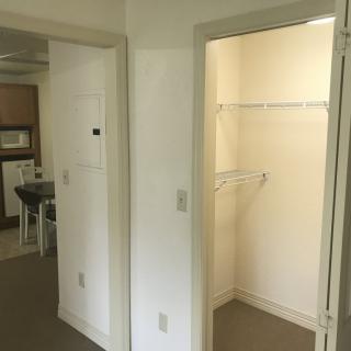 An interior view of an apartment showing a hallway with a closet and part of the kitchen.