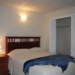 A cozy bedroom with a neatly made bed and a small lamp on the side table.