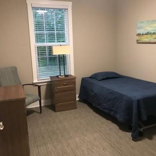 A simple bedroom with a single bed, nightstand, and desk.