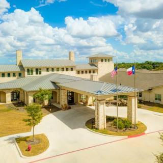 Aerial view of a large building complex with flags and a circular driveway under a partly cloudy sky.