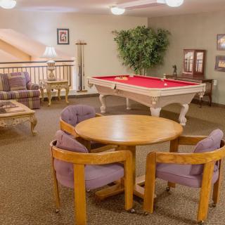 A cozy game room featuring a red-felt pool table, comfortable seating, and stylish decor.