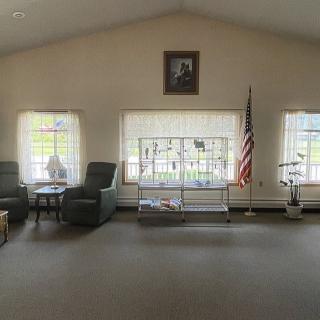 A quiet living room with chairs, large windows, and an American flag.