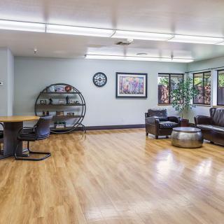 A spacious waiting room with seating, a desk, and wood flooring.