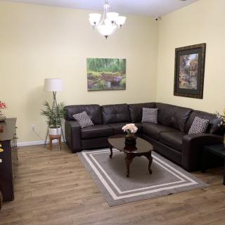 A cozy living room with a black sectional sofa, wooden floors, and stylish decor.
