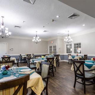 An elegantly decorated dining area with neatly arranged tables and chairs, enhanced by chandelier lighting.