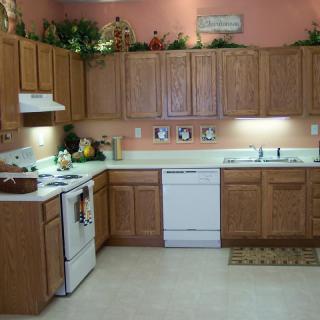 A cozy kitchen with wooden cabinets, white appliances, and decorative items on the upper shelves.