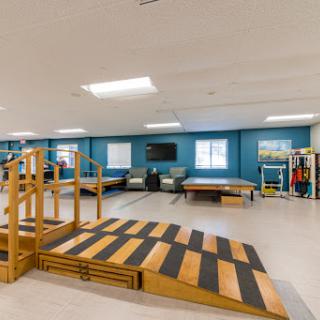 A spacious therapy room equipped with a wooden ramp and exercise areas for rehabilitation.