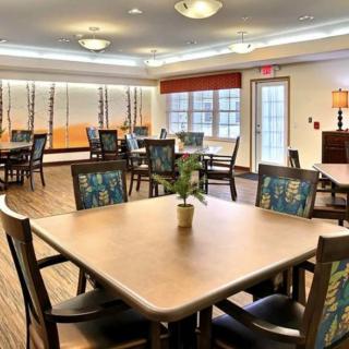 A well-lit dining area with multiple tables and chairs, featuring modern decor and lighting.