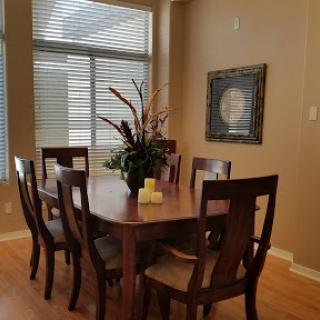 A well-lit dining room featuring a wooden table and chairs, adorned with floral decor, creating a warm and inviting atmosphere.