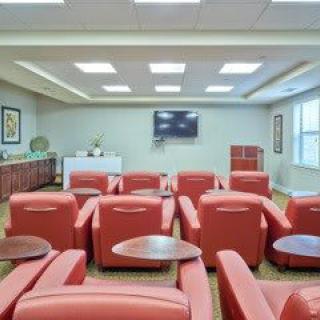 A cozy lounge area with red chairs and a television on the wall.